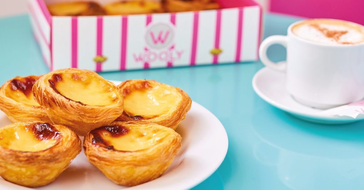 Pastéis de nata Wooly sur une assiette avec la boîte rayée et un café