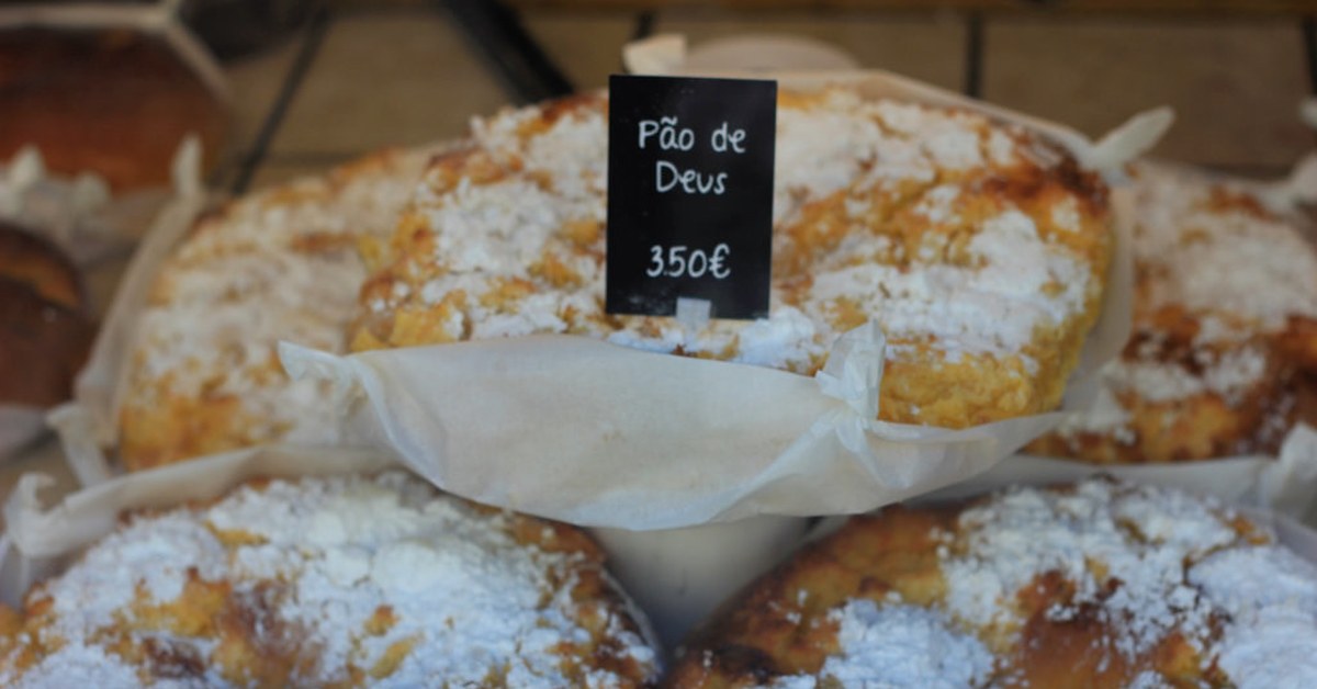 Pães de Deus dorés, saupoudrés de sucre glace, sur l'étal d'une boulangerie portugaise